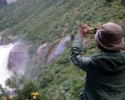 person taking a photo of a waterfall during a clear day