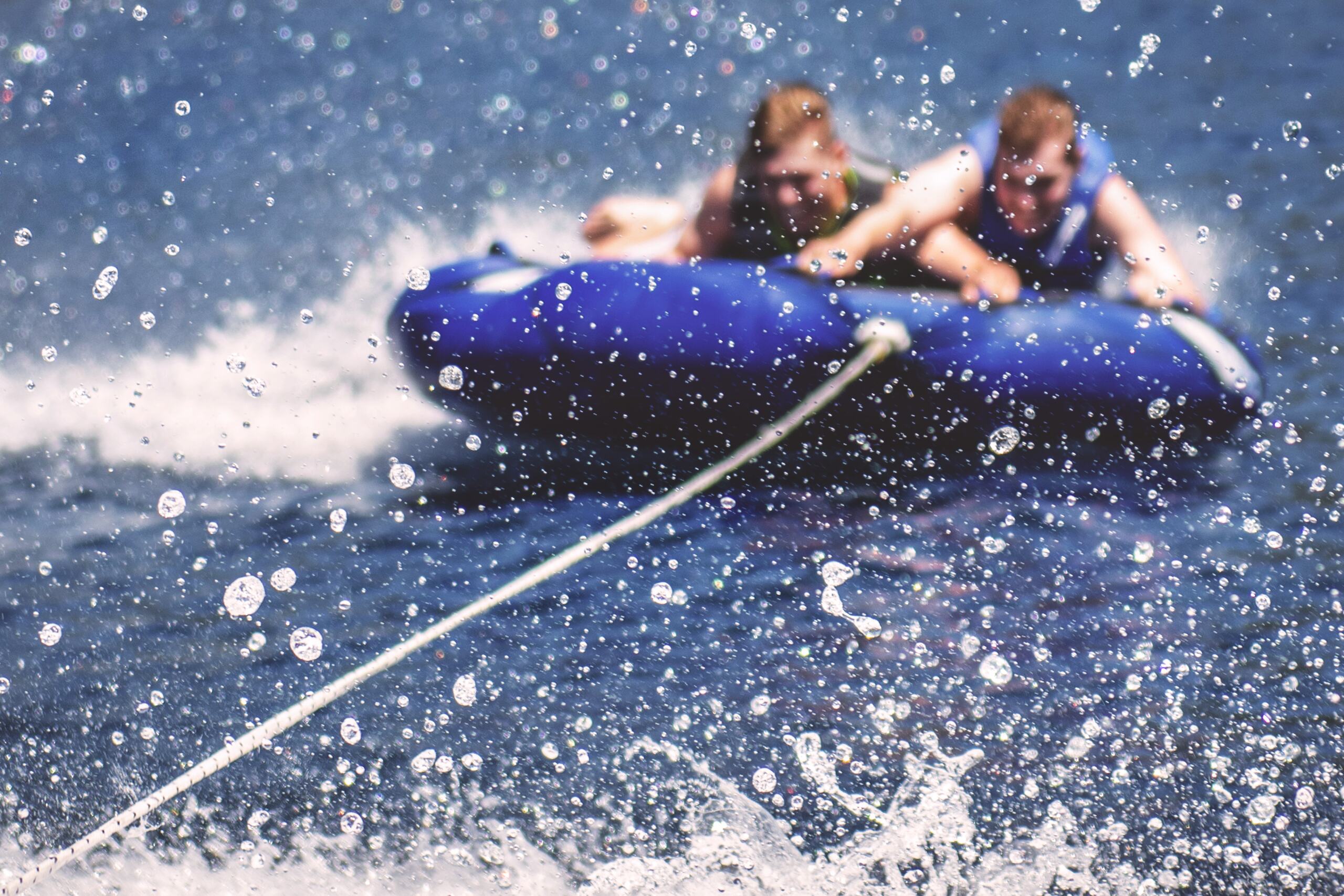 two-men-in-an-inflatable-boat-with-water-splashes-all-around two men in an inflatable boat with water splashes all around